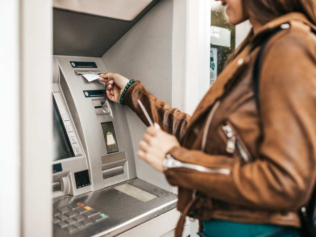 a woman with medium tan skin typing retrieving her receipt for her transaction at the ATM from her personal checking account