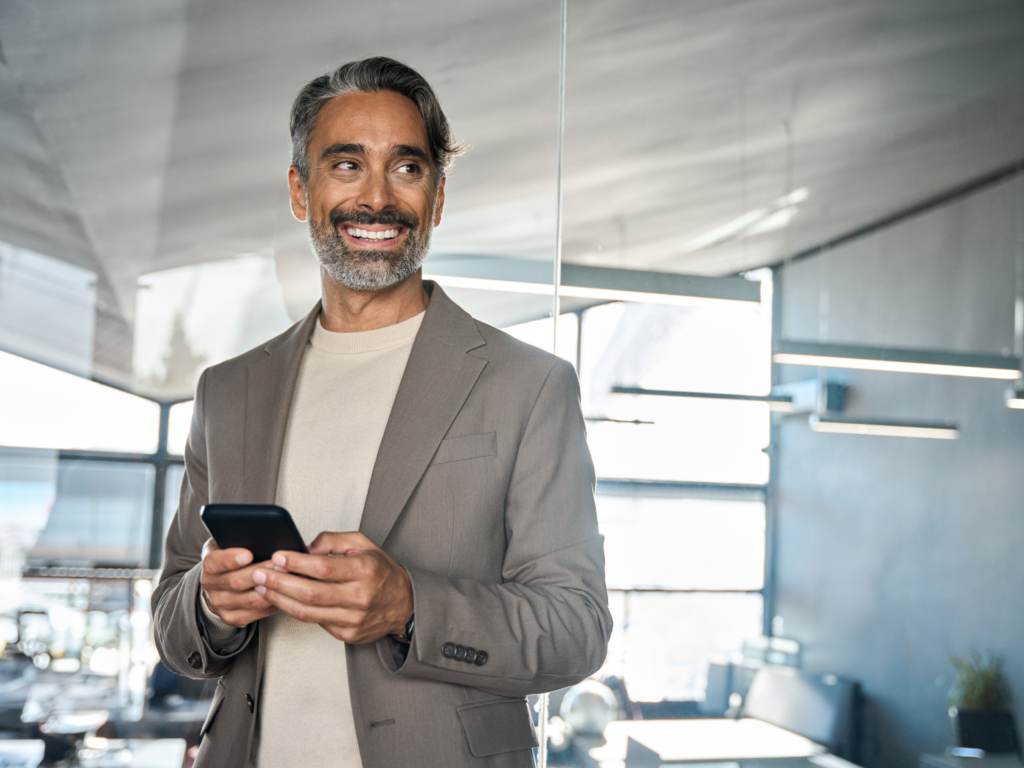 a middle aged estate attorney with medium brown skin and black and gray hair reviews SBA 7(a)  loan options on his phone with his preferred lending partner